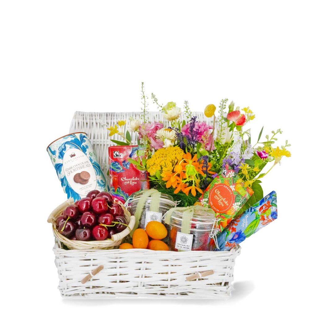 Cesta de frutas y dulces con flores